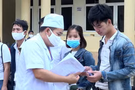 Nhân viên y tế trao giấy chứng nhận hoàn thành thời gian cách ly cho công dân. (Ảnh: Nguyễn Nam/TTXVN)