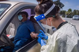 Nhân viên y tế lấy mẫu xét nghiệm COVID-19 cho người dân tại Inglewood, California (Mỹ). (Ảnh: AFP/TTXVN)