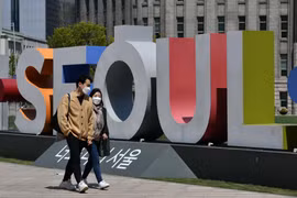 Người dân đeo khẩu trang phòng lây nhiễm COVID-19 trên một đường phố ở Seoul,Hàn Quốc. (Ảnh: AFP/TTXVN)