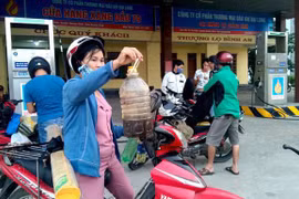 Can xăng mua ở Cửa hàng xăng dầu số 79, đóng trên địa bàn xã Võ Ninh, huyện Quảng Ninh chuyển sang màu vàng đen, có nhiều cặn ở đáy can. (Ảnh: Văn Tý/TTXVN)