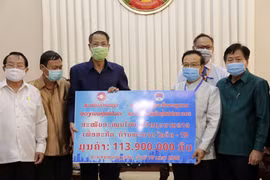Ông Nguyễn Duy Trung (trái), Chủ tịch Tổng hội người Việt Nam tại Lào, trao cho Phó Thủ tướng, Bộ trưởng Tài chính Lào Somdy Duangdy số tiền ủng hộ. (Ảnh: Phạm Kiên/Vietnam+)