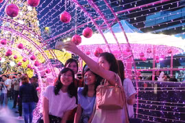 Du khách chụp ảnh tại một trung tâm mua sắm ở thủ đô Bangkok. (Nguồn: THX/TTXVN)