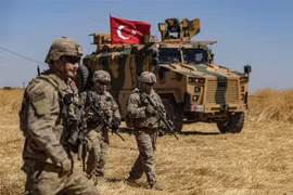 Binh sỹ Mỹ và xe quân sự của Thổ Nhĩ Kỳ tham gia cuộc tuần tra chung ở ngoại ô thị trấn Tal Abyad (Syria) giáp giới với Thổ Nhĩ Kỳ. (Ảnh: AFP/TTXVN)