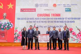 Ông Phạm Đức Ấn - Chủ tịch Hội đồng thành viên Agribank trao tặng quà của Agribank hỗ trợ hộ cận nghèo, đối tượng chính sách quận Hà Đông (Hà Nội) nhân dịp Tết Nguyên đán Giáp Thìn. (Ảnh: Vietnam+)