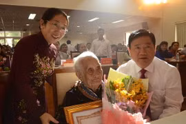 Bí thư Thành ủy Thành phố Hồ Chí Minh Đinh La Thăng trao bằng chứng nhận Bà mẹ Việt Nam Anh hùng cho mẹ Nguyễn Thị Trong. (Ảnh: Nguyễn Cúc/TTXVN)