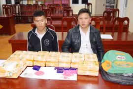 Đối tượng Thào A Già (bên trái) và Liều A Súa (bên phải) cùng tang vật vụ án. (Ảnh: TTXVN phát)