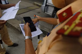 Kiểm tra mã QR trên thẻ nhận diện của các phương tiện vận tải thiết yếu. (Ảnh: Nam Sương/TTXVN)