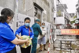  Tình nguyện viên, đoàn viên thanh niên Thành phố Hồ Chí Minh vận chuyển thực phẩm, nhu yếu phẩm để gửi đến người dân tại một khu vực cách ly tại quận Tân Phú. (Ảnh: Hồng Giang/TTXVN)