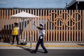 Nhân viên hướng dẫn cho các phương tiện tại lối vào làng vận động viên Olympic và Paralympic ở Tokyo, Nhật Bản, ngày 15/7/2021. (Ảnh: AFP/TTXVN)