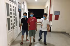 Di lý đối tượng Nguyễn Thành Nhật Minh sau khi bị bắt. (Ảnh: TTXVN phát)