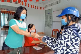 Trao tiền hỗ trợ cho người bán vé số. (Ảnh: TTXVN)