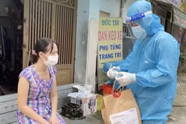 Nhân viên y tế trạm y tế lưu động phường 25, quận Bình Thạnh cấp phát túi thuốc cho F0 điều trị tại nhà. (Ảnh: Đinh Hằng/TTXVN)