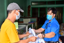 Trao quà cho công nhân ở trọ, người nghèo trong khu phong tỏa. (Ảnh: TTXVN phát)
