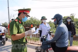 Các lực lượng chức năng kiểm tra 'giấy thông hành' của người dân khi qua chốt kiểm soát dịch COVID-19. (Ảnh minh họa: Thanh Thương/TTXVN)