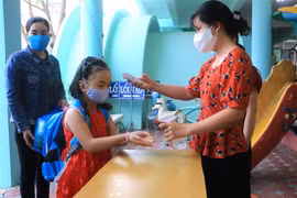 Đo thân nhiệt, rửa tay cho trẻ trước khi vào lớp. (Ảnh: Lê Thúy Hằng/TTXVN)