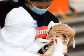 Lấy mẫu xét nghiệm cho một cháu nhỏ tại phường Yên Hòa (Cầu Giấy). (Ảnh: Huy Hùng/TTXVN)