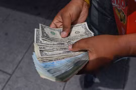 Người dân kiểm đếm đồng USD và tiền bolivar Venezuela trên đường phố Caracas (Venezuela). (Ảnh: AFP/TTXVN)