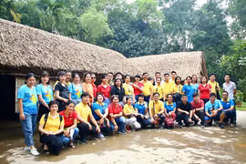Tập thể ban lãnh đạo và cán bộ nhân viên Báo điện tử VietnamPlus chụp ảnh lưu niệm trước ngôi nhà của cụ Phó bảng Nguyễn Sinh Sắc ở làng Sen. (Ảnh: Nguyễn An/Vietnam+)