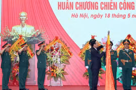 Chủ tịch nước Võ Văn Thưởng gắn Huân chương Chiến công hạng Nhất lên lá cờ truyền thống của Tổng Cục II, Bộ Quốc phòng. (Ảnh: Thống Nhất/TTXVN)