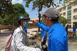Thí sinh được kiểm tra thân nhiệt trước khi vào điểm thi. (Ảnh: Phạm Mai/Vietnam+)