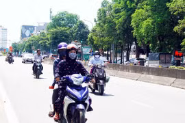 Người dân đều trang bị khẩu trang và mặc áo chống nắng kín khi di chuyển trên đường trong thời tiết nắng nóng. (Ảnh: Tá Chuyên/TTXVN)