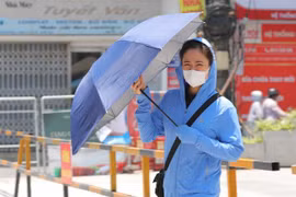 Một người dân trang bị nhiều đồ chống nắng, nóng khi phải di chuyển ngoài trời. (Ảnh: Hoàng Hiếu/TTXVN)
