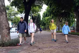 Các vị khách du lịch nước ngoài cũng chuẩn bị cho mình áo khoác mỏng để đón gió lạnh tại hồ Hoàn Kiếm (Hà Nội). (Ảnh: Danh Lam/TTXVN)