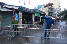 Lực lượng chức năng hướng dẫn người dân di chuyển khỏi khu vực giáp ranh chợ Nhân Chính. (Ảnh: Tuấn Anh/TTXVN) 