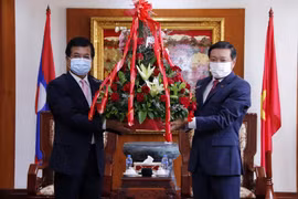Phó Trưởng Ban Đối ngoại Trung ương Đảng Nhân dân Cách mạng Lào Somphone Sichaleun (trái) trao hoa cho Đại sứ Nguyễn Bá Hùng, chúc mừng 76 năm Quốc khánh Việt Nam. (Ảnh: Phạm Kiên/TTXVN)
