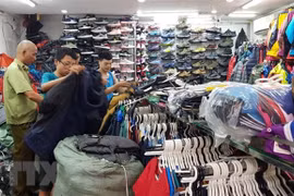 Lực lượng quản lý thị trường kiểm tra, phát hiện nhiều sản phẩm giả thương hiệu The North Face tại cửa hàng kinh doanh quần áo, giầy dép số 62 Lò Sũ, quận Hoàn Kiếm. (Ảnh: Trần Việt/TTXVN) 