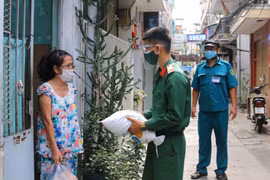 Các chiến sỹ Trung đoàn 88, Sư đoàn 302 (Quân Khu 7) cùng với Ban Chỉ huy quân sự phường 8 Quận 10 trao tặng lương thực, thực phẩm tận nhà cho người lao động nghèo hẻm 139 Nguyễn Tiểu La, Quận 10. (Ảnh: Thanh Vũ/TTXVN) 