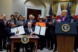 Đại sứ Nhật Bản Shinsuke Sugiyama và Đại diện Thương mại Mỹ Robert Lighthizer giơ Hiệp định Thương mại Mỹ-Nhật Bản bên cạnh Tổng thống Donald Trump và đại biểu hai nước, trong lễ ký tại Nhà Trắng. (Nguồn: Reuters) 
