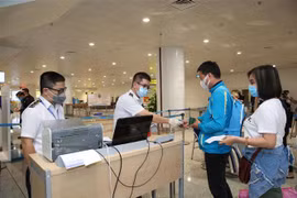Nhân viên y tế kiểm tra phiếu khai báo y tế của hành khách trước khi làm thủ tục nhập cảnh tại cửa khẩu Sân bay quốc tế Nội Bài (Hà Nội), chiều 7/3. (Ảnh: Dương Giang/TTXVN)