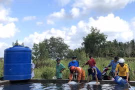 Người dân vùng hạn, mặn xã Thạnh Phú Đông, huyện Giồng Trôm, tỉnh Bến Tre vui mừng nhận nước ngọt được trao tặng. (Ảnh: TTXVN phát)