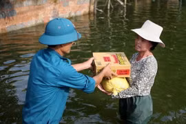 Quà hỗ trợ của Hội Chữ thập Đỏ thành phố Hà Nội được giao tận tay người dân trong vùng ngập. (Ảnh: Thanh Tùng/TTXVN)