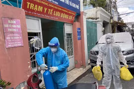 Lực lượng Quân y tại Trạm y tế lưu động số 1 (Phường 6, quận Tân Bình) mang các đồ dùng cần thiết (bình oxy, máy đo nồng độ oxy, ống nghe, nhiệt kế, dung dịch sát khuẩn, khẩu trang…) để đến nhà F0. (Ảnh: Mạnh Linh/TTXVN)