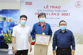 Ông Lê Xuân Thành, Trưởng Ban tổ chức Giải (trái) và nhà thơ Trần Đăng Khoa, Chủ tịch Hội đồng giám khảo (phải) trao giải cho tác giả Bình Ca (giữa). (Ảnh: Hòa Nguyễn/Vietnam+)