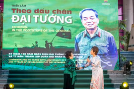 Nhà thơ Nguyễn Thị Mỹ Dung (trái) và ca sỹ Mỹ Linh ngẫu hứng trong lễ khai mạc triển lãm. (Ảnh: Minh Sơn/Vietnam+)