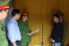 Cơ quan chức năng đọc quyết định khởi tố vụ án, khởi tố bị can và lệnh tạm giam 2 tháng đối với Ngô Xuân Sĩ (áo đen) về hành vi lạm dụng tín nhiệm, chiếm đoạt tài sản, là hàng hóa cứu trợ người dân vùng lũ lụt. (Ảnh: Văn Tý/TTXVN)