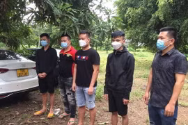Bốn đối tượng tìm đường xuất cảnh trái phép và tài xế cùng xe ôtô đang bị tạm giữ tại Đồn Biên phòng cửa khẩu Chàng Riệc. (Ảnh: Thanh Tân/TTXVN)