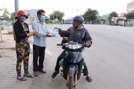 Tặng các suất cơm, nước uống miễn phí cho những người trở về quê bằng xe máy từ các tỉnh, thành phía Nam trên Quốc lộ 1A đoạn qua thành phố Phan Rang-Tháp Chàm, tỉnh Ninh Thuận. (Ảnh: Nguyễn Thành/TTXVN)