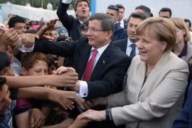 Thủ tướng Đức Angela Merkel (phải) và Thủ tướng Thổ Nhĩ Kỳ Ahmet Davutoglu gặp gỡ những người tị nạn trong chuyến thăm Gaziantep. (Nguồn: THX/TTXVN)
