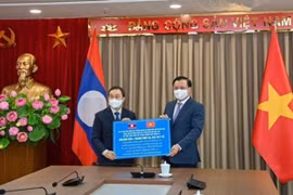 Bí thư Thành ủy Hà Nội Đinh Tiến Dũng trao quà tặng hỗ trợ Thủ đô Vientiane và 8 khu vực Bắc Lào để phòng, chống COVID-19. (Ảnh: TTXVN phát)