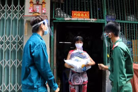 Các chiến sỹ Trung đoàn 88, Sư đoàn 302 (Quân Khu 7) cùng với Ban Chỉ huy quân sự phường 8, Quận 10 trao tặng lượng thực, thực phẩm tận nhà cho người lao động nghèo hẻm 139 Nguyễn Tiểu La, Quận 10. (Ảnh: Thanh Vũ /TTXVN)