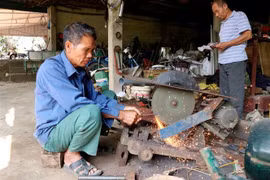 Ông Nguyễn Văn Hoàn với công việc chế tạo, cải tiến máy móc phục vụ sản xuất nông nghiệp. (Ảnh: Quang Cường/TTXVN)