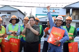Thủ tướng Phạm Minh Chính tặng quà, động viên công nhân đang thi công tuyến đê kè ứng phó biến đổi khí hậu tại sông Cần Thơ, thuộc Dự án phát triển thành phố Cần Thơ. (Ảnh: Văn Điệp/TTXVN)