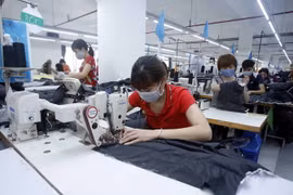 Công nhân sản xuất sản phẩm may mặc. (Ảnh: Phạm Kiên/TTXVN)