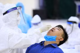 Nhân viên y tế của quận Cầu Giấy, Hà Nội tiến hành lấy mẫu dịch hầu họng để xét nghiệm bằng phương pháp RT-PCR của người dân từ Đà Nẵng trở về. (Ảnh: Thành Đạt/TTXVN)