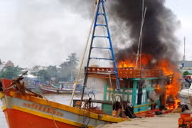 Lực lượng Biên phòng Sóc Trăng cùng nhân dân tham gia chữa cháy tàu cá của ngư dân. (Ảnh: Trung Hiếu/TTXVN)