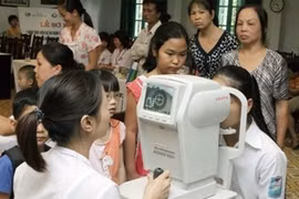 Nhân viên y tế khám mắt cho học sinh. (Ảnh: TTXVN)
